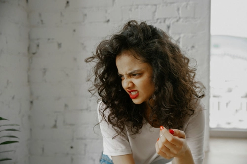 Angry young woman with curly hair showing furious expression