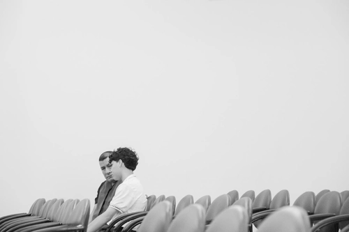 Black-and-white photo of two men sitting in empty auditorium chairs