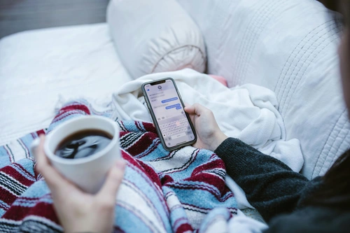 Person checking phone texts under blanket, overthinking messages