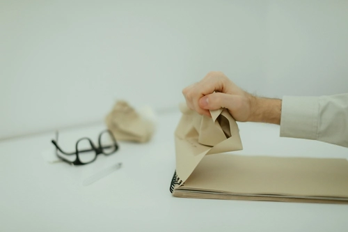 Hand crumpling pages of a spiral notebook