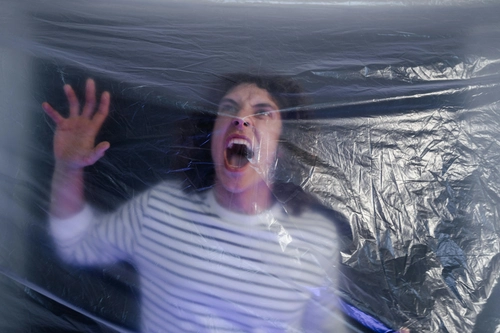 Panicked man shouting and pressing hands against transparent plastic sheet