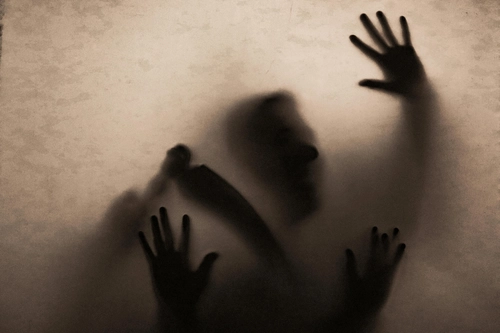 Blurry shadow of trapped person pounding hands against translucent fabric
