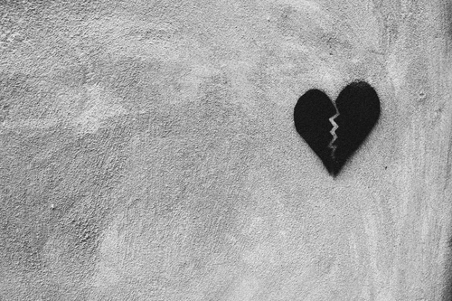 Broken heart graffiti spray-painted on a wall, symbolizing heartbreak and relationship end.